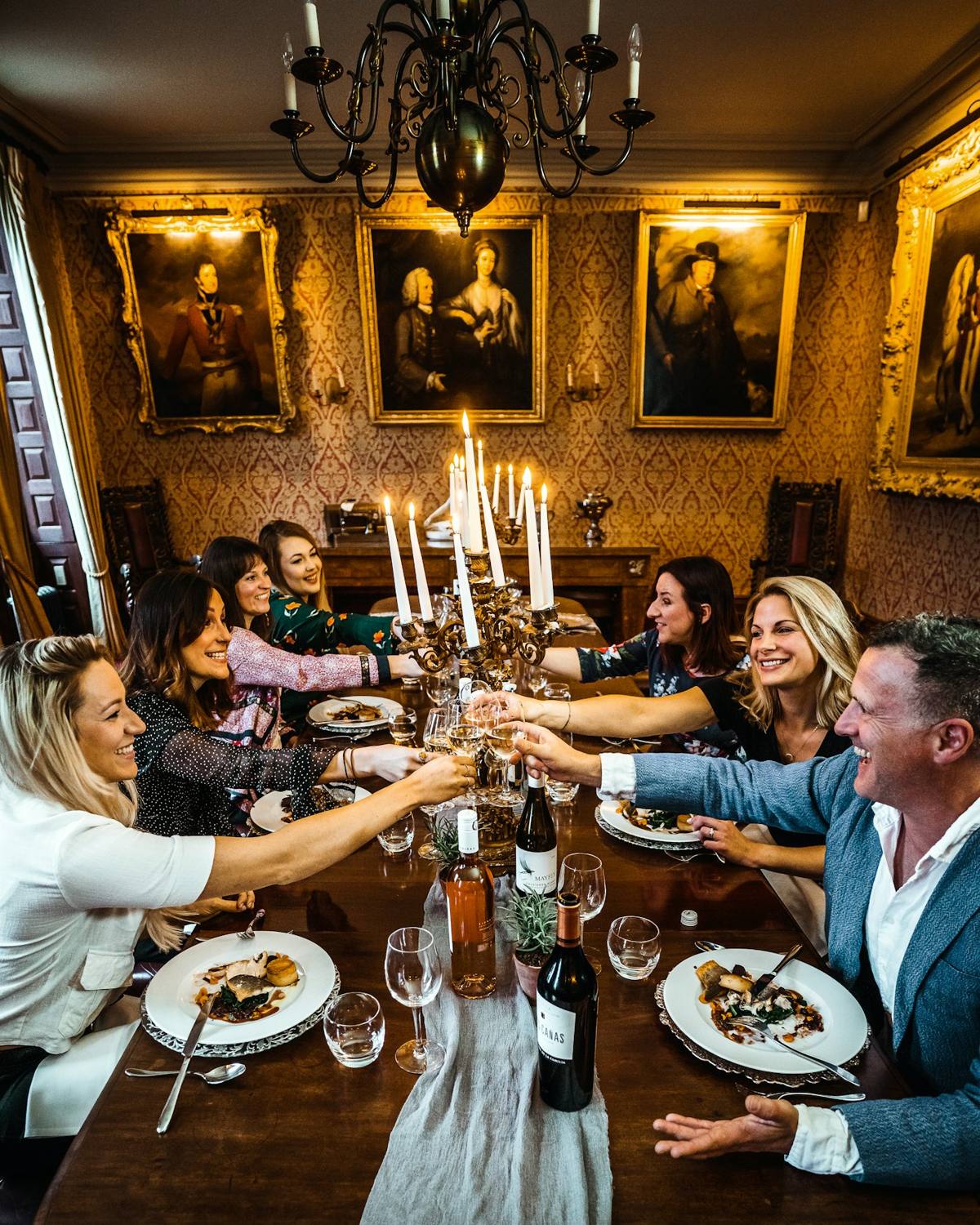 A group toasting at a long candlelit table